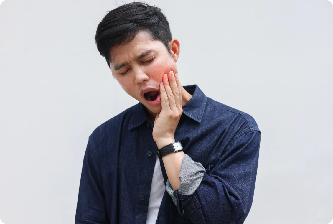 Man holding jaw in pain, yawning.